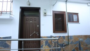 A staircase with a metal handrail leading to a brown door with a window above it. - Idrizi Apartment (Berat)