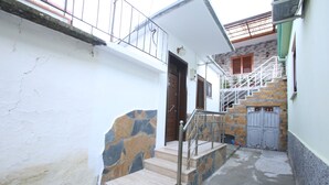 A narrow stairway leading to a wooden door, with a stone wall on one side and a white wall on the other. - Idrizi Apartment (Berat)