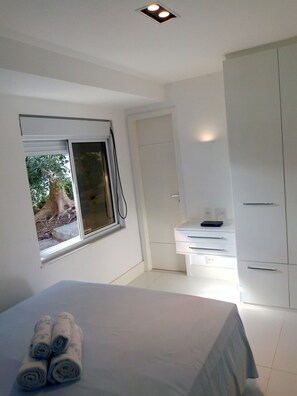 A bedroom with a bed, a window, a wardrobe, and a desk.