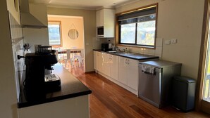 A compact kitchen with a coffee machine, a microwave, and a dishwasher. - Shelby s Lodge- lovely light filled home (Venus Bay)