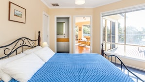 A bedroom with a bed, a window, and a door leading to a balcony.