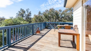 A wooden deck with a blue railing, a table, and chairs.