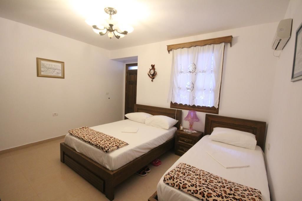 Un dormitorio con dos camas, una araña, una ventana con cortinas y un aire acondicionado de pared.