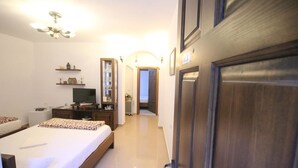 A hotel room with a bed, bedside table, TV, and a wooden wardrobe. - Guesthouse Altin (Berat)