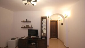 A living room with a TV, shelves, and a door leading to another room. - Guesthouse Altin (Berat)