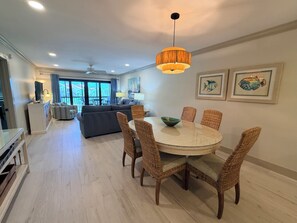 A dining area with wicker chairs and a round table, a ceiling fan, and artwork on the walls. - Updated Gulf View Condo in Beautiful Siesta Dunes, 5-205 (Siesta Key)