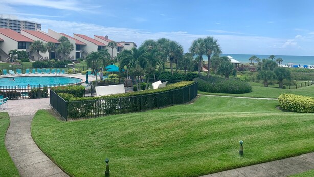 A resort with a swimming pool, palm trees, and a view of the ocean. - Updated Gulf View Condo in Beautiful Siesta Dunes, 5-205 (Siesta Key)