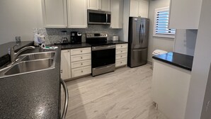 A modern kitchen with white cabinets, stainless steel appliances, and a granite countertop. - Updated Gulf View Condo in Beautiful Siesta Dunes, 5-205 (Siesta Key)