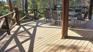 A wooden deck with tables and chairs, surrounded by a wooden railing. - The Nest—Tranquil Bush Retreat near Dunsborough (Yallingup)