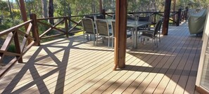 Terraza de madera con mesas y sillas, rodeada por una barandilla de madera.
