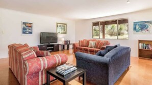A living room with a TV, two sofas, a coffee table, and artwork on the walls. - The Nest—Tranquil Bush Retreat near Dunsborough (Yallingup)