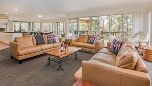 A spacious living area with leather sofas, a coffee table, and a dining area with chairs. - The Nest—Tranquil Bush Retreat near Dunsborough (Yallingup)