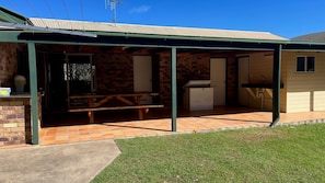 A covered outdoor area with a picnic table, a barbecue grill, and a small kitchen area. - Baker - Rainbow Beach. Walk to Everything! Including the beach and main street. (Rainbow Beach)