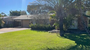 A residential property with a well-maintained lawn, a brick house, and a palm tree. - Baker - Rainbow Beach. Walk to Everything! Including the beach and main street. (Rainbow Beach)