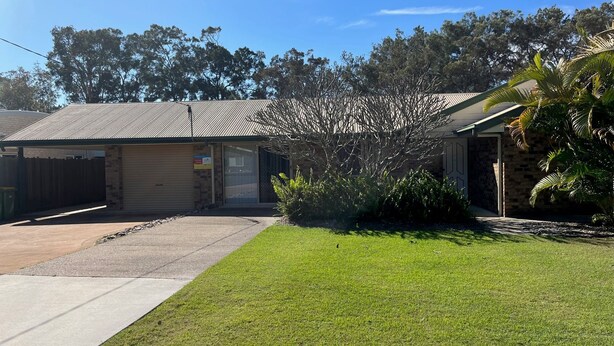 A single-story building with a garage, a small lawn, and a tree in front. - Baker - Rainbow Beach. Walk to Everything! Including the beach and main street. (Rainbow Beach)