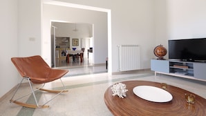 A modern living room with a brown leather chair, a wooden coffee table, and a flat-screen TV on a blue stand. - Villa Aurelia (Castellana Grotte)