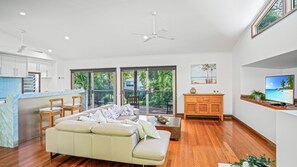 Relax in a spacious living area with a sofa, TV, and sliding door to a lush outdoor space.