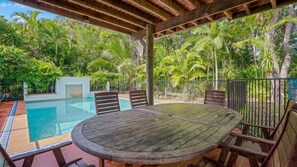 Relax by the pool surrounded by lush tropical vegetation and a pergola structure.