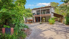 Set amidst lush greenery, this two-story house offers a covered outdoor area with a deck.