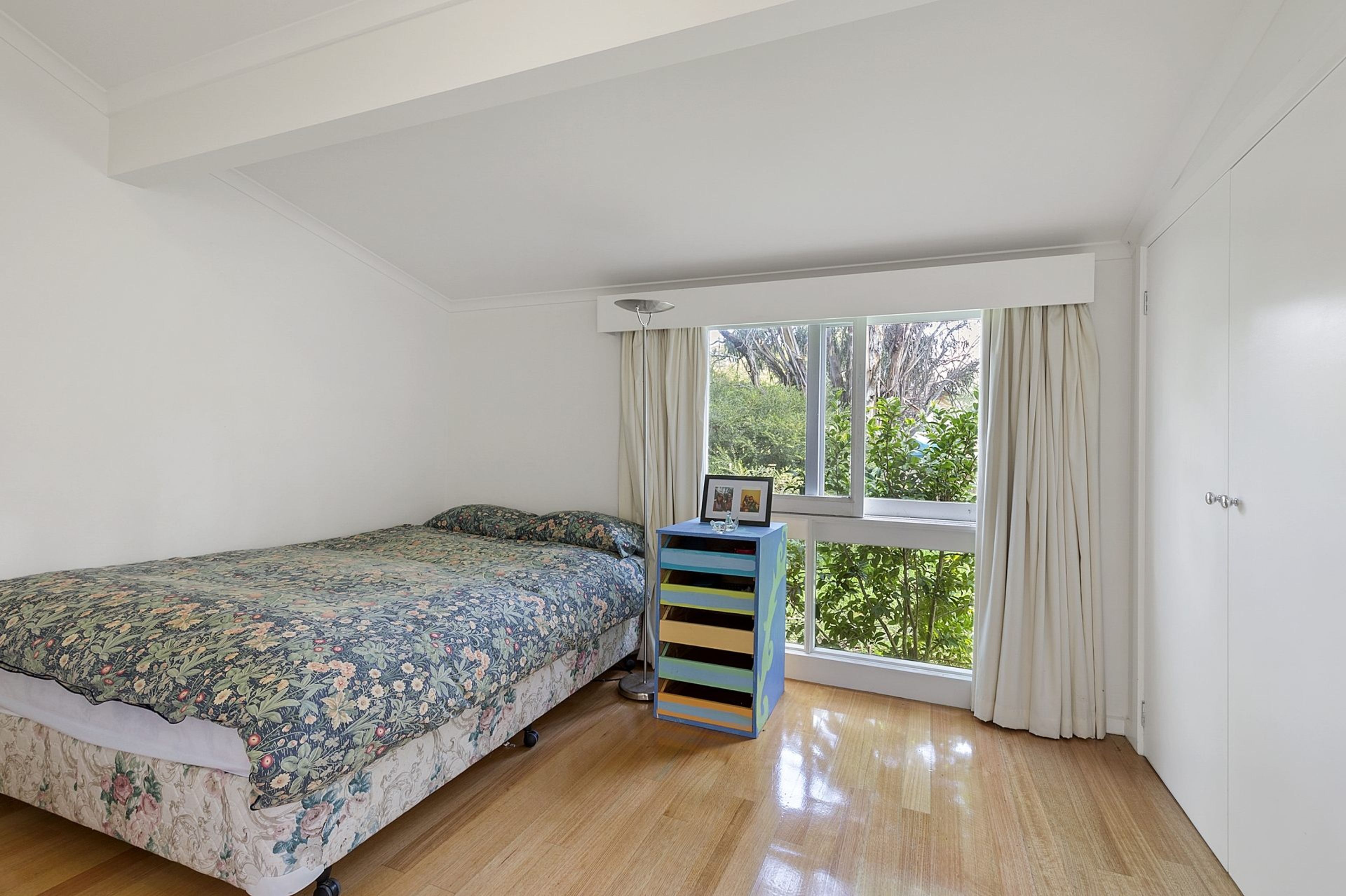 Un dormitorio con una cama individual, una ventana con cortinas y un armario empotrado.