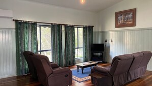 Een woonkamer met twee bruine fauteuils, een salontafel en een televisie op een dressoir.
