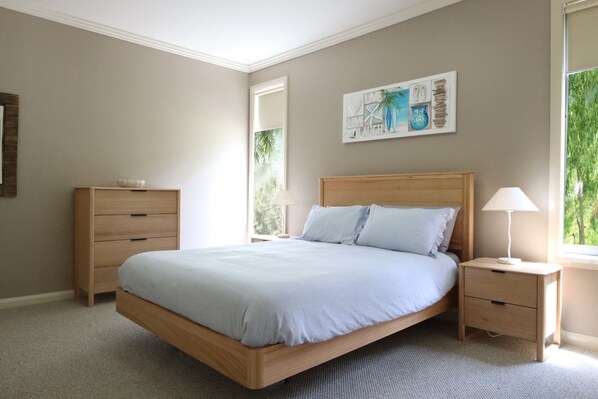 A bedroom with a bed, a nightstand, a dresser, and a window with a view of greenery. - Craiglee (Lorne)