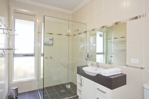 A modern bathroom with a glass shower enclosure, a vanity with a sink, and a mirror.