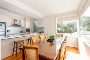 A modern kitchen with white cabinetry, a stainless steel range hood, and a large island with bar stools.