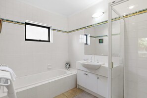 A modern bathroom with a bathtub, a sink, and a shower. - Fernview (Lorne)