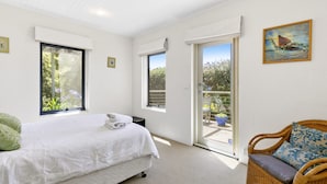 Une chambre avec un lit, une chaise et un balcon donnant sur un paysage verdoyant.