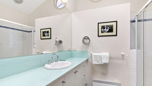 A modern bathroom with a glass shower enclosure, a sink with a faucet, and two framed pictures on the wall. - Fernview (Lorne)