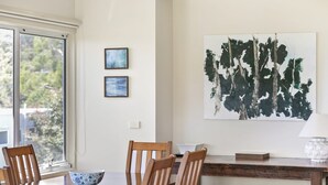 A dining area with a table, chairs, a bowl, and a painting on the wall. - Fernview (Lorne)