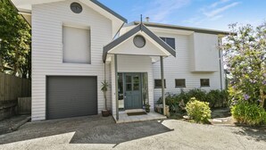 Une maison à deux étages avec un garage, une véranda et une porte d’entrée.