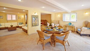 A spacious living area with a dining table surrounded by wicker chairs, a sofa, and a window with blinds. - 3 Min Walk to Beach - Blessed Manor (4 Bed House) (Hastings)