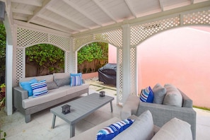 A covered outdoor seating area with two sofas and a coffee table, surrounded by a white lattice structure.