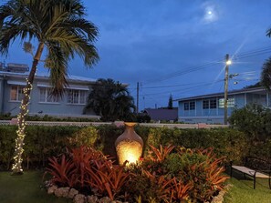 A garden with a large decorative vase, a palm tree, and a bench. - 3 Min Walk to Beach - Blessed Manor (4 Bed House) (Hastings)