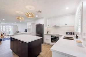 Une cuisine moderne avec des meubles blancs, un îlot central et des luminaires suspendus.