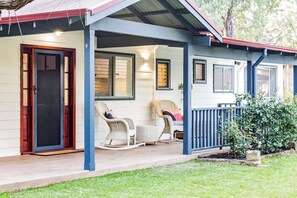 Ein Haus mit Veranda, zwei Schaukelstühlen und einer Tür.