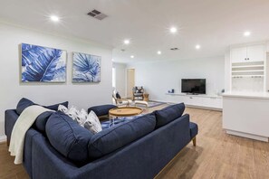 Un salon moderne avec un canapé bleu, une table basse et un téléviseur.