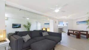 Ein modernes Wohnzimmer mit einer Eckcouch, einem Esstisch und einer Küche im Hintergrund.