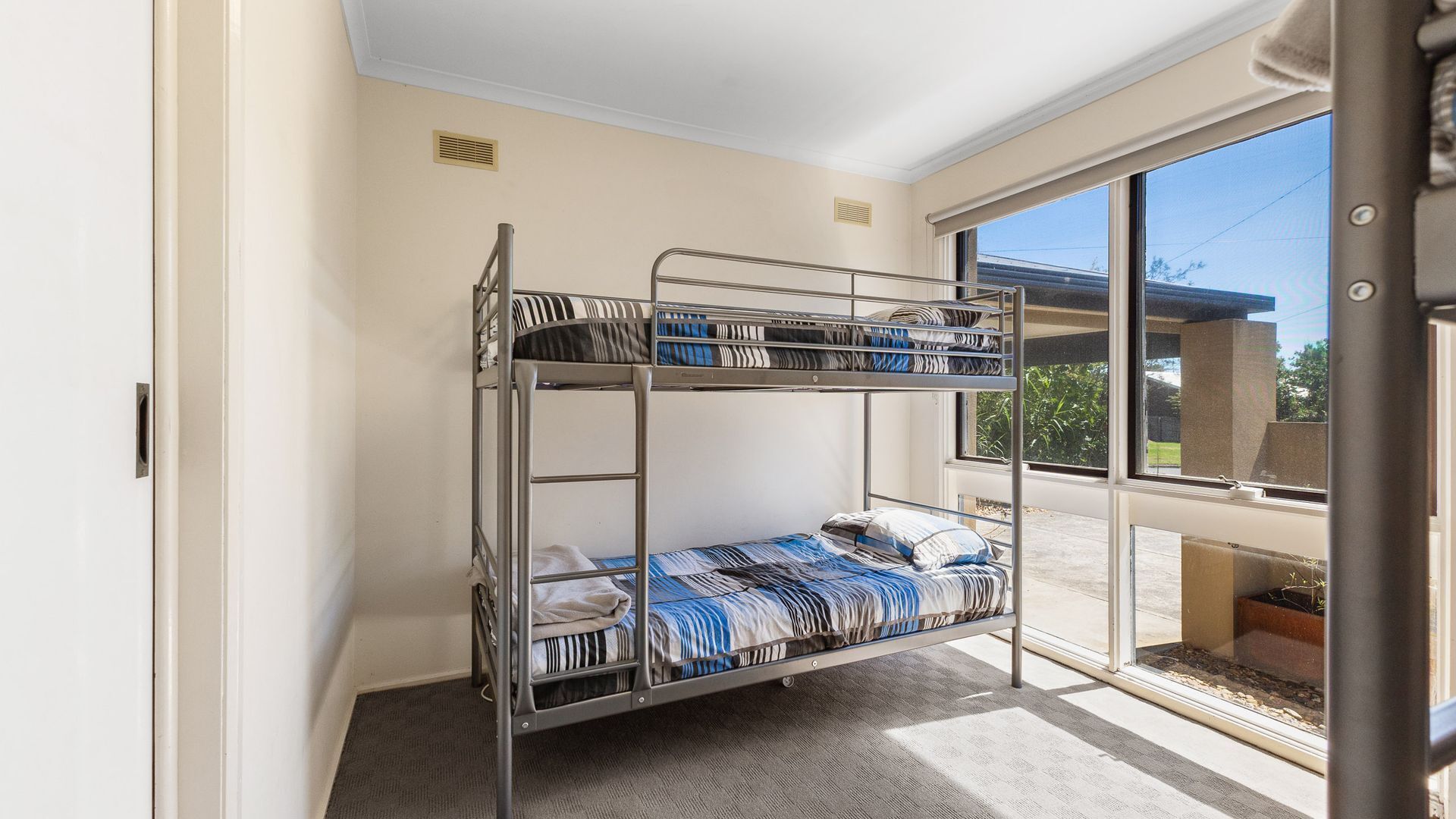 A bunk bed with striped bedding in a room with a large window and a view of the outside.