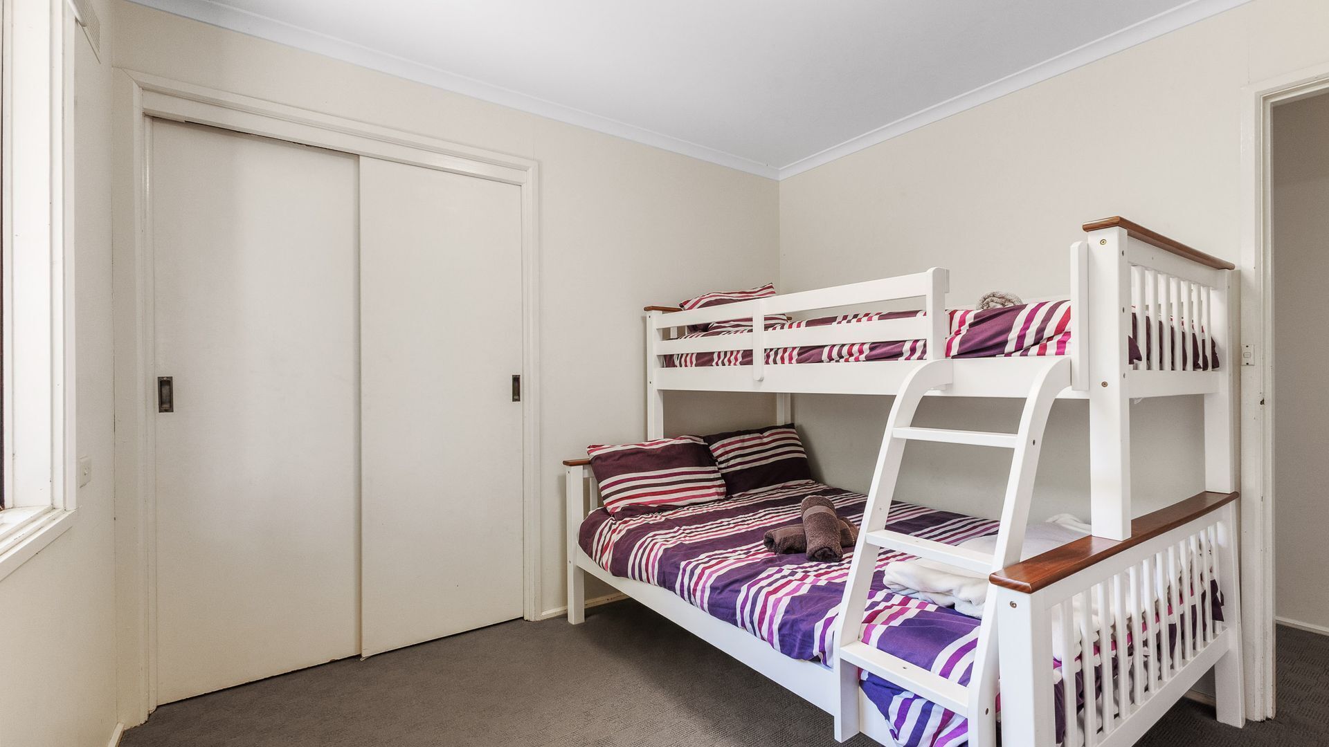 A bunk bed room with a closed door and a window.