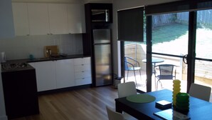 Cozinha moderna com armários brancos, forno embutido e área de jantar com mesa e cadeiras.