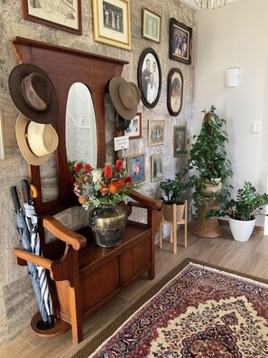 A wooden bench with hats and umbrellas, a mirror, and a sign.