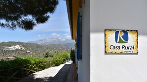 Ein ländliches Haus mit einem Schild, auf dem 'Casa Rural Superior' steht, und Blick auf Berge im Hintergrund.