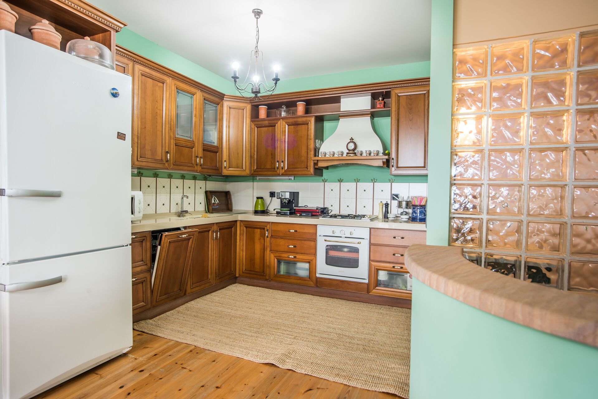 A kitchen with wooden cabinets, a white refrigerator, a stove, and a tiled backsplash.