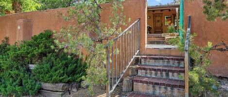 A staircase leading to a building with a rustic exterior, surrounded by greenery and trees.