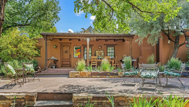 A rustic building with a patio area featuring outdoor furniture and plants. - Casa Verano | Cozy Eastside Adobe Retreat (Santa Fe)