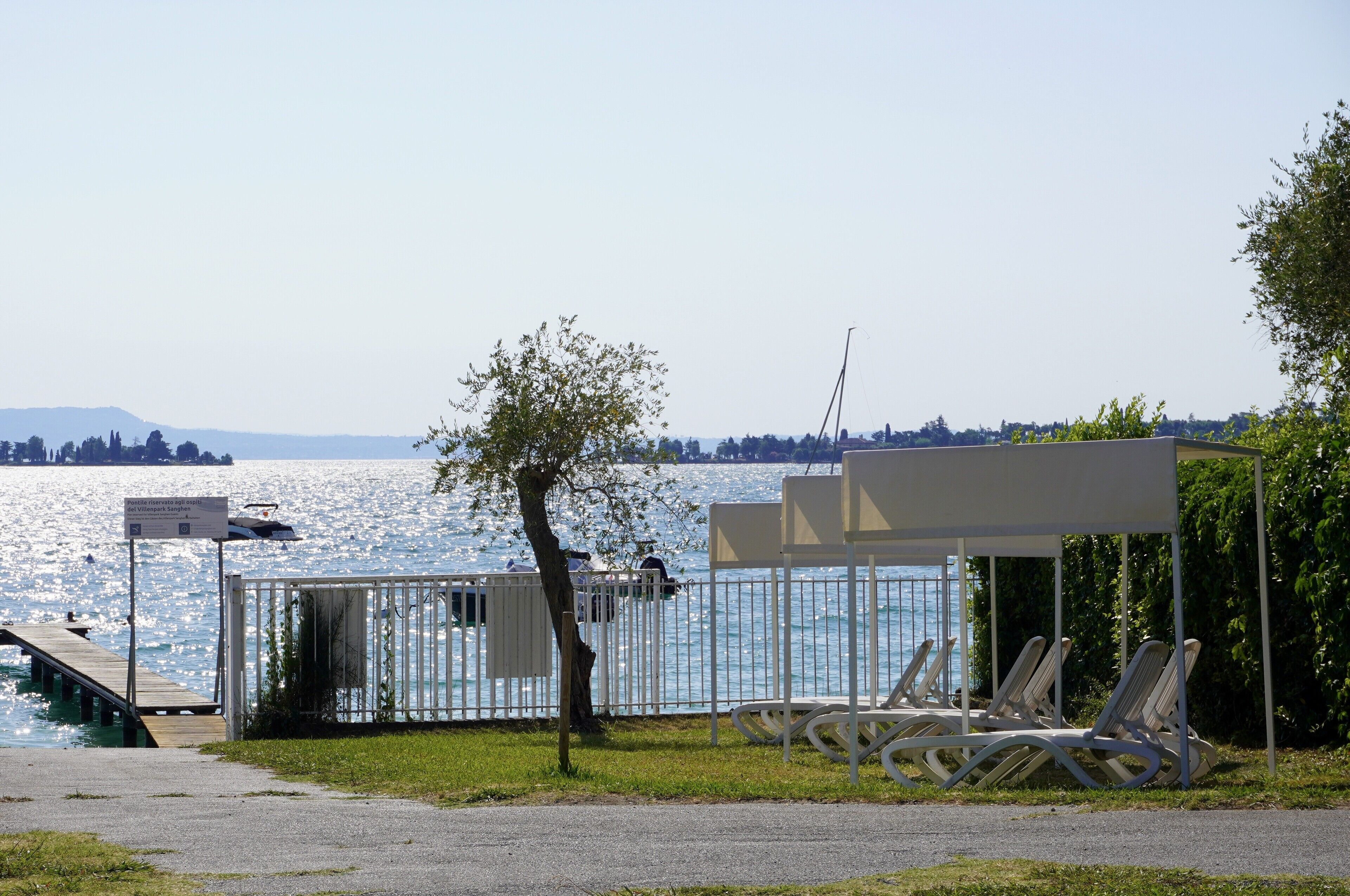 A lakeside setting with a dock, a covered seating area with lounge chairs, and a small kiosk.