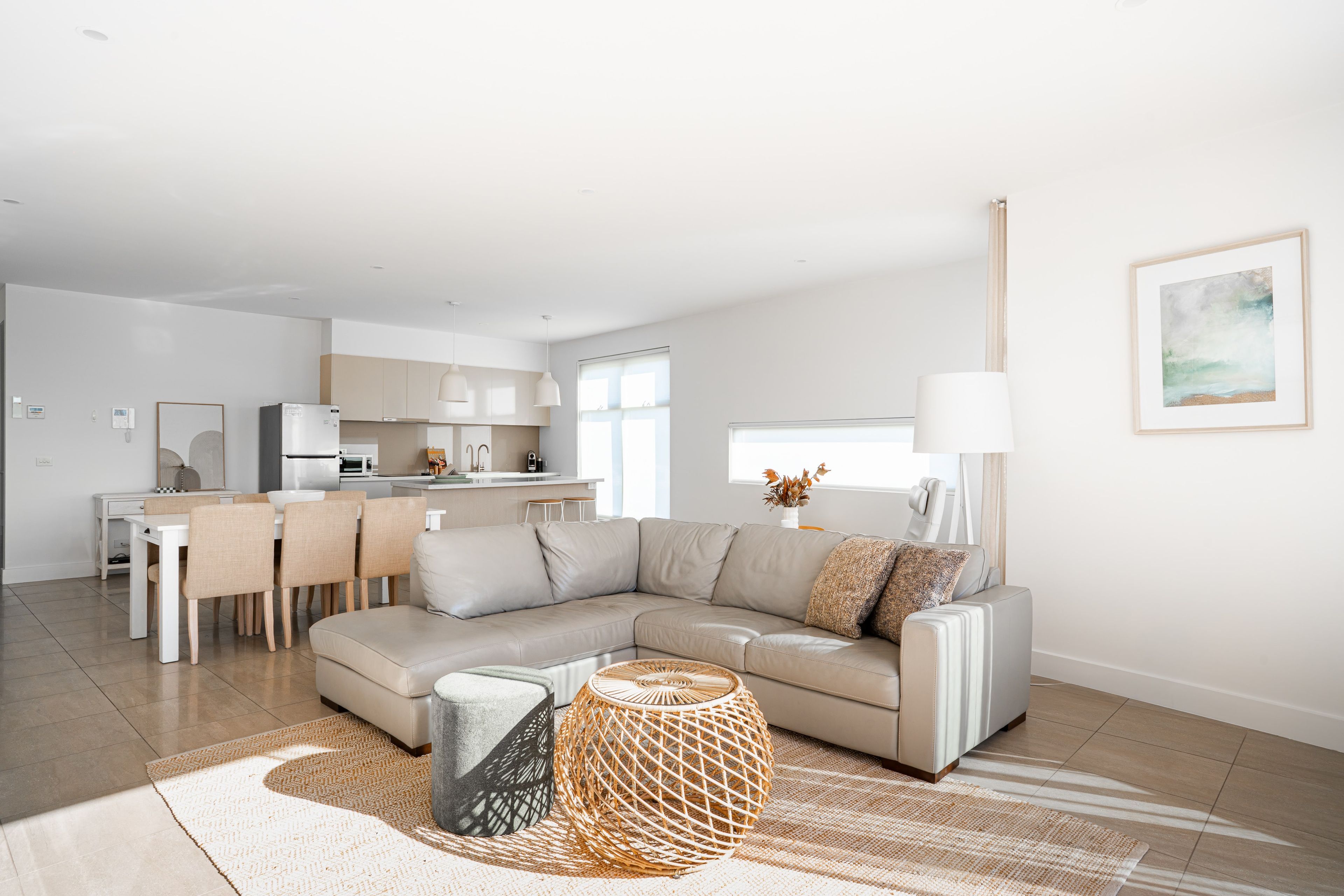 A modern living room with a sectional sofa, a dining area, and a kitchen in the background.